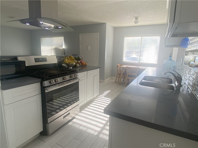 kitchen featuring island exhaust hood, stainless steel gas range oven, a textured ceiling, sink, and white cabinetry