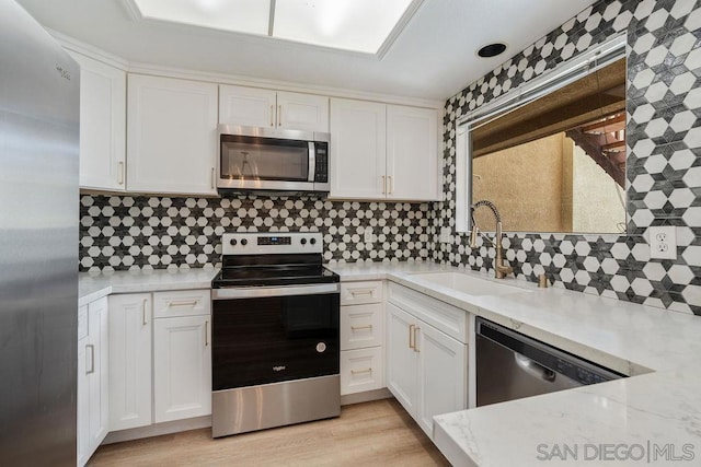 kitchen featuring white cabinets, sink, stainless steel appliances, and light hardwood / wood-style flooring