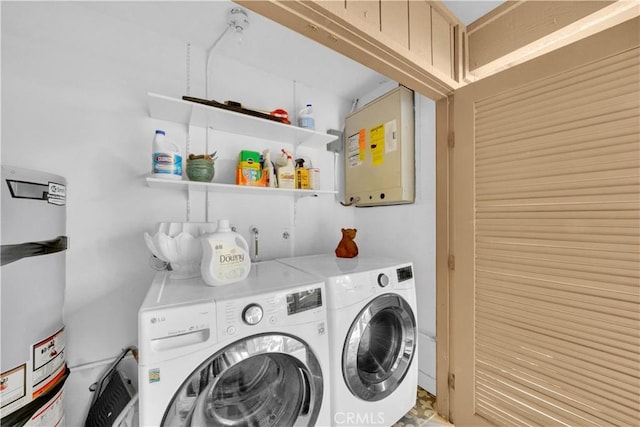 washroom featuring strapped water heater and washer and dryer