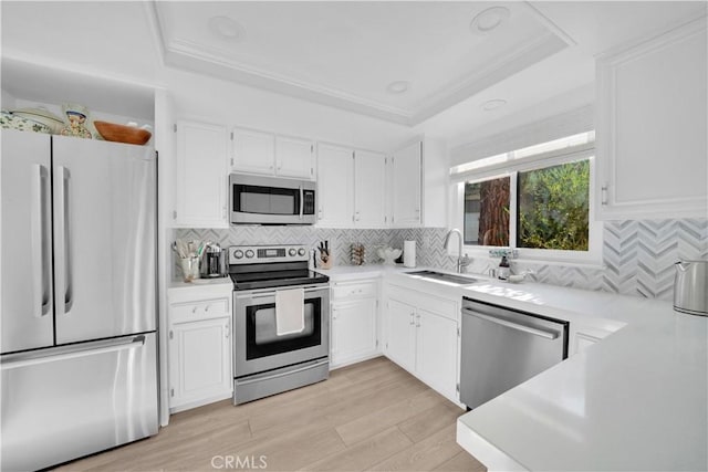 kitchen with tasteful backsplash, stainless steel appliances, a tray ceiling, sink, and white cabinets