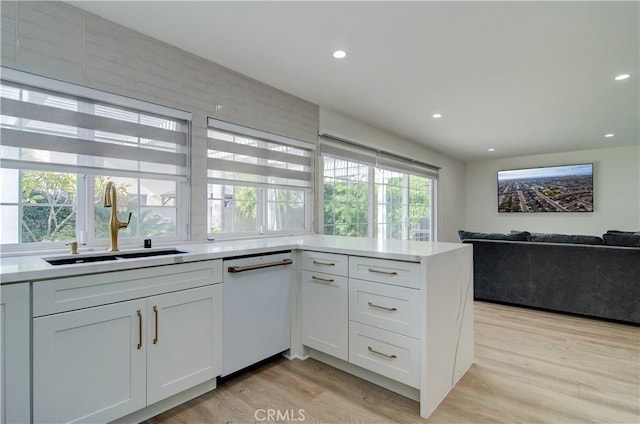 kitchen featuring white cabinets, light hardwood / wood-style flooring, dishwasher, and sink