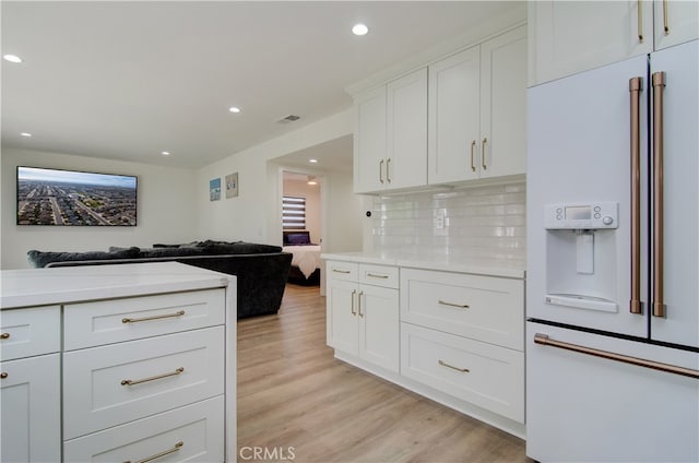 kitchen with tasteful backsplash, white cabinetry, high end fridge, and light hardwood / wood-style floors