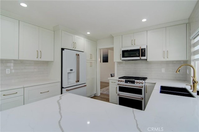 kitchen featuring white appliances, sink, hardwood / wood-style flooring, decorative backsplash, and white cabinetry