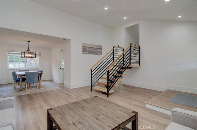 living room with light hardwood / wood-style floors, vaulted ceiling, and a notable chandelier