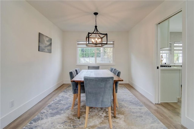 dining area with a notable chandelier and light hardwood / wood-style flooring