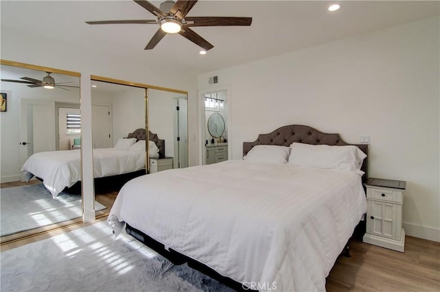 bedroom with multiple closets, ceiling fan, and light wood-type flooring