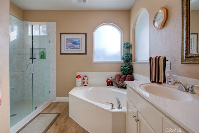 bathroom with vanity, hardwood / wood-style flooring, independent shower and bath, and a healthy amount of sunlight