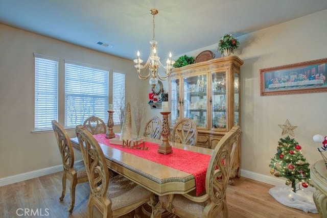 dining area with light hardwood / wood-style floors and an inviting chandelier