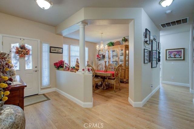 foyer featuring a chandelier, decorative columns, light hardwood / wood-style flooring, and a wealth of natural light