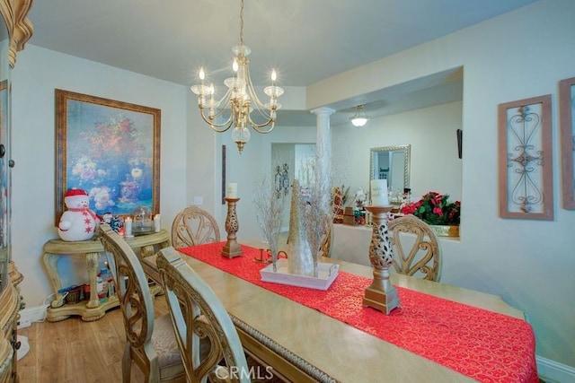 dining space featuring hardwood / wood-style floors, an inviting chandelier, and ornate columns