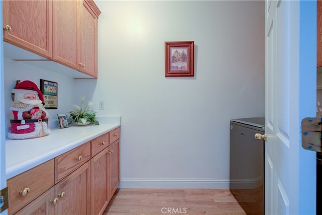 clothes washing area with cabinets and light hardwood / wood-style floors