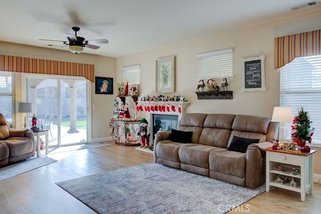 living room with light hardwood / wood-style floors, ceiling fan, and a healthy amount of sunlight