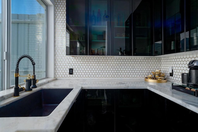 kitchen featuring backsplash, light stone counters, and sink