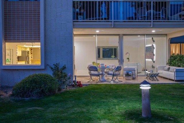 doorway to property featuring a lawn, a balcony, and a patio