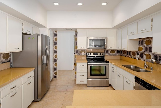 kitchen with sink, white cabinets, stainless steel appliances, and light tile patterned floors