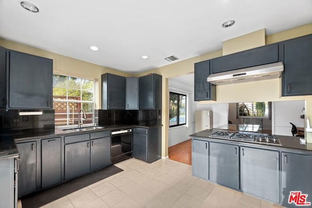 kitchen with stainless steel gas cooktop, sink, light tile patterned floors, black dishwasher, and range hood