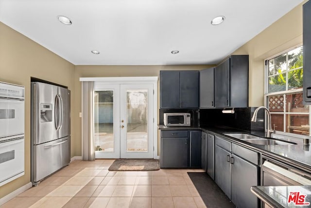 kitchen featuring sink, french doors, stainless steel appliances, tasteful backsplash, and light tile patterned floors