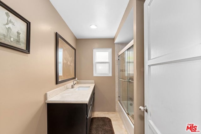 bathroom featuring tile patterned flooring, vanity, and bath / shower combo with glass door