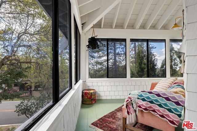 sunroom / solarium featuring vaulted ceiling with beams and a healthy amount of sunlight