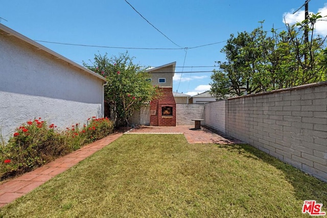 view of yard with a brick fireplace and a patio area