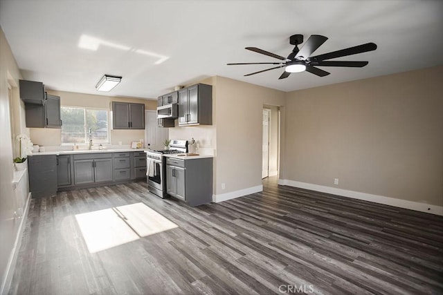 kitchen with appliances with stainless steel finishes, ceiling fan, sink, gray cabinets, and dark hardwood / wood-style floors