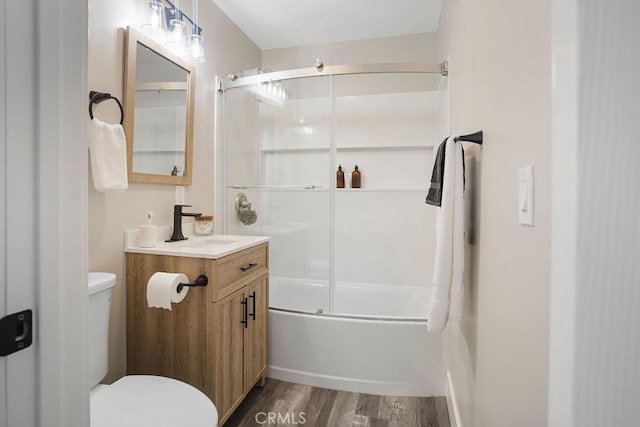 full bathroom featuring hardwood / wood-style floors, vanity, enclosed tub / shower combo, and toilet