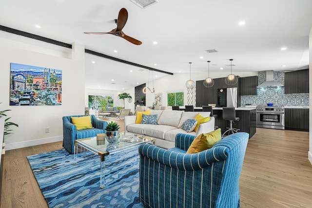 living room with ceiling fan, lofted ceiling with beams, and light wood-type flooring