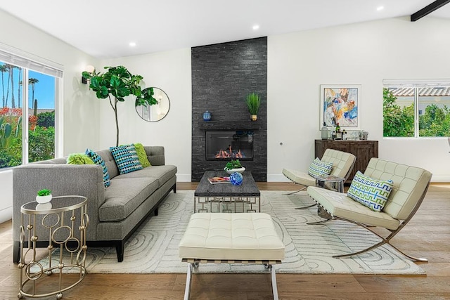 living room with a fireplace, vaulted ceiling with beams, and light hardwood / wood-style floors