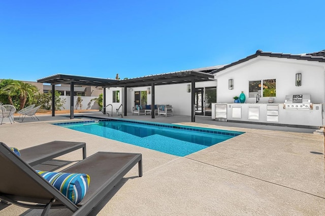 view of pool featuring an outdoor kitchen, area for grilling, a patio area, and sink