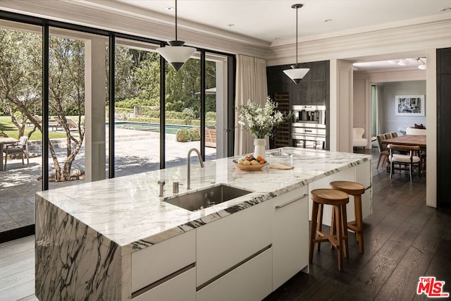 kitchen featuring pendant lighting, sink, a kitchen island with sink, and white cabinets