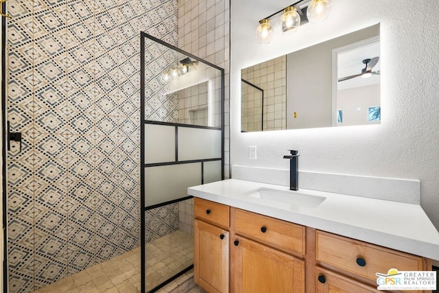 bathroom featuring ceiling fan, vanity, and tiled shower