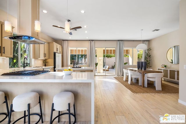 kitchen with ceiling fan, kitchen peninsula, hanging light fixtures, and light hardwood / wood-style flooring