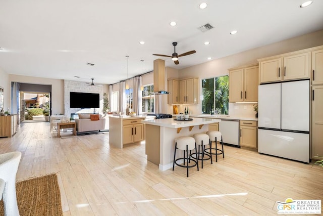 kitchen featuring a center island, white appliances, ceiling fan, light hardwood / wood-style floors, and a breakfast bar area