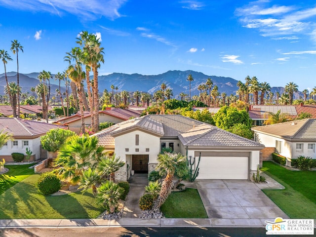 view of front of house featuring a mountain view, a garage, and a front lawn