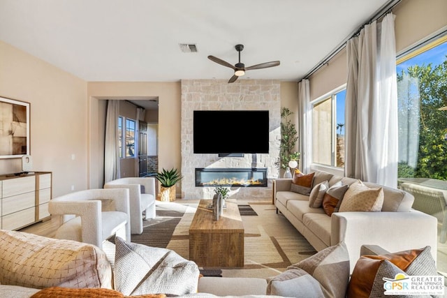 living room with ceiling fan and a fireplace