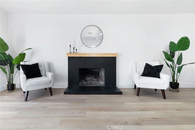 sitting room with light hardwood / wood-style floors and a tiled fireplace