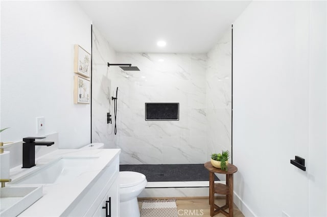 bathroom with vanity, toilet, baseboard heating, and a tile shower