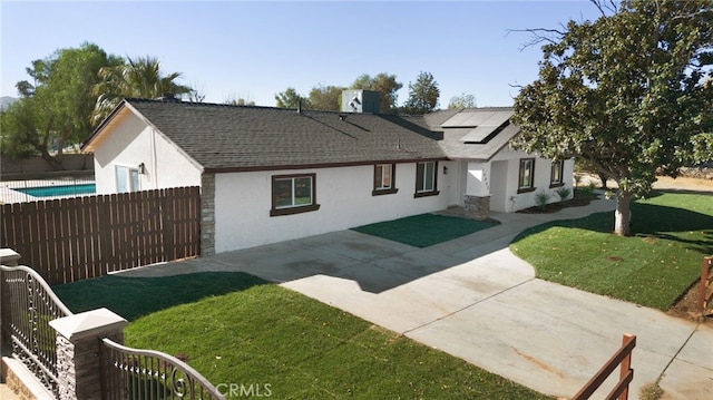 view of front of house featuring solar panels, central AC, a front lawn, and a patio area