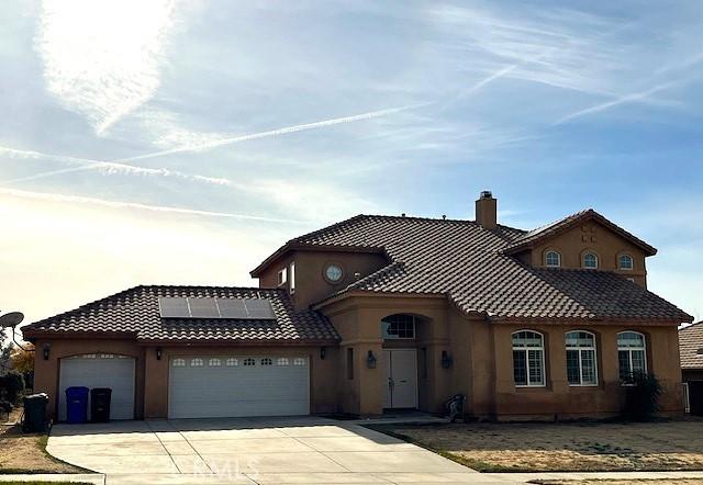 mediterranean / spanish house featuring solar panels and a garage