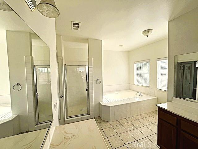 bathroom with tile patterned floors, vanity, and shower with separate bathtub