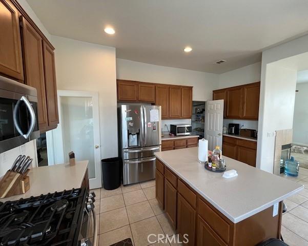 kitchen featuring appliances with stainless steel finishes, a center island, and light tile patterned flooring