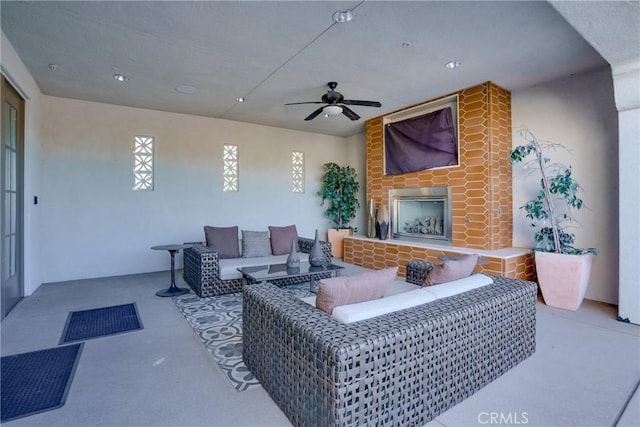 living room featuring ceiling fan, a healthy amount of sunlight, and exterior fireplace