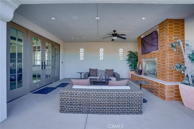 view of patio / terrace featuring an outdoor living space with a fireplace, ceiling fan, and french doors