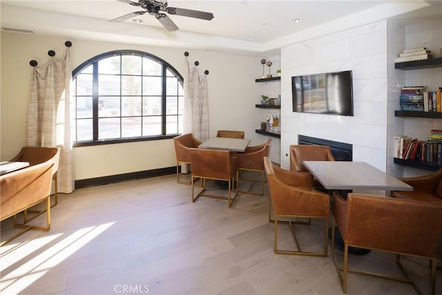 sitting room featuring a fireplace, light hardwood / wood-style flooring, and ceiling fan