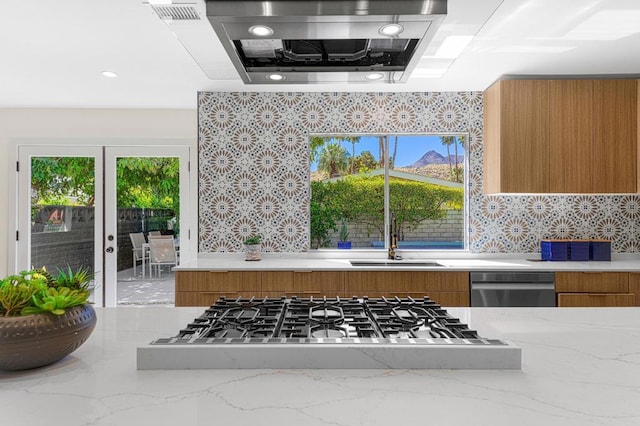 kitchen featuring light stone counters, sink, stainless steel appliances, and range hood