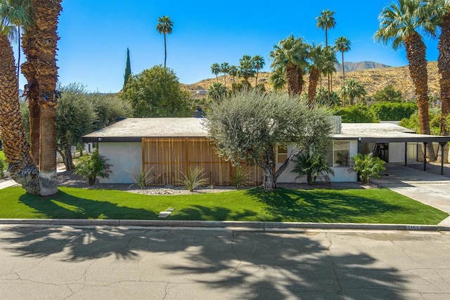 view of front facade featuring a mountain view, a front lawn, and a carport