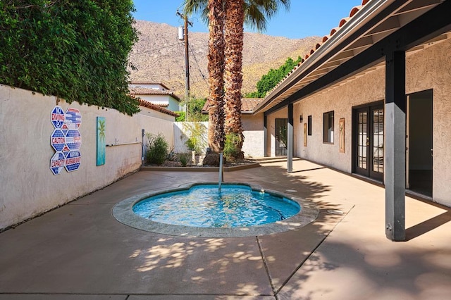 view of swimming pool featuring a mountain view, a community hot tub, a patio, and french doors