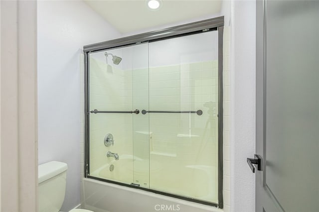 bathroom featuring bath / shower combo with glass door and toilet