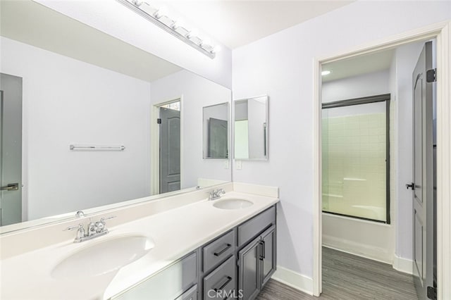 bathroom with hardwood / wood-style flooring, vanity, and combined bath / shower with glass door