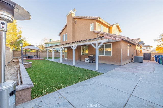 rear view of property with a gazebo, a patio area, a lawn, and central AC